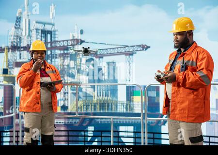 Technicians working together on offshore platform, doing site inspection using drone. Coworkers use aerial photography tech to determine optimal locations for drilling pipelines Stock Photo