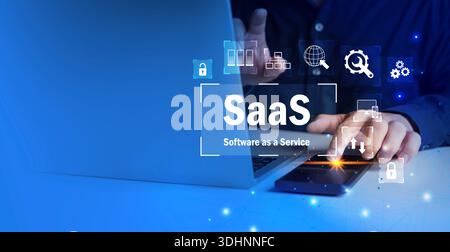 Businessman using laptop and smartphone with SaaS software as a service text and digital icons, representing cloud computing, subscription platforms, Stock Photo