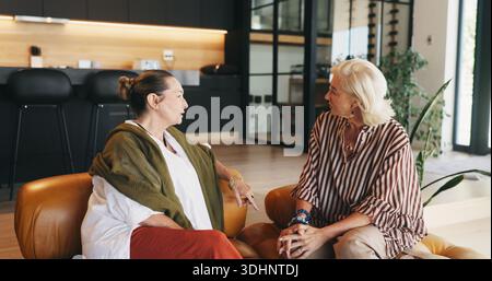 Relax, senior women and friends in home for conversation, gossip and bonding together on weekend. Elderly people, talking and chill in living room for Stock Photo