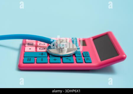 A calculator with medical instruments and a stethoscope on a blue background, a place for text, the concept of the cost of medical services Stock Photo