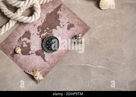 Modern compass, world map, seashells and rope on grey grunge background Stock Photo