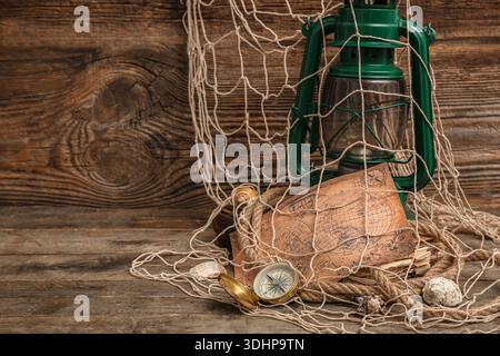 Golden compass, net, world map, lantern and seashells on wooden background Stock Photo