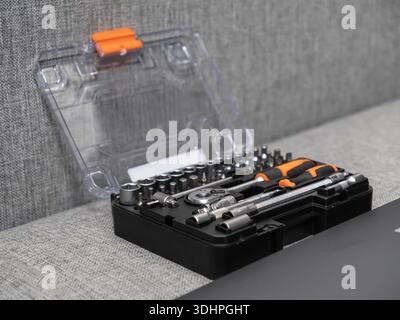 A professional black tool kit with a clear open lid reveals an organized assortment of metal socket wrenches, various bits, and an orange-handled scre Stock Photo