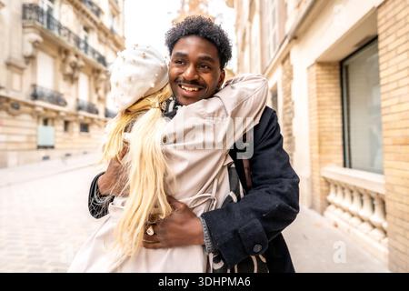 Happy diverse couple hugging on paris street Stock Photo