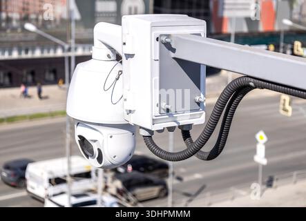 Surveillance CCTV camera mounted on post against the city street, close up Stock Photo
