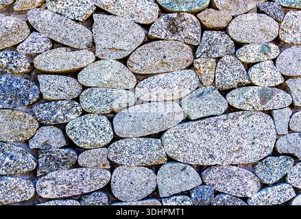Rough stone wall as creative background texture. Natural stones masonry with uneven seams. Stone wall background Stock Photo