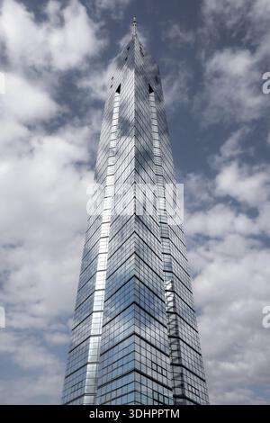 View of the sleek, modern Fukuoka Tower piercing the sky, its glass facade reflecting the scattered clouds and blue sky above, Fukuoka, Fukuoka, Japan Stock Photo