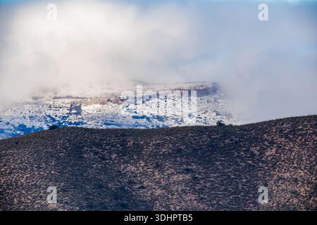 A dramatic view of the Aitana mountains near Villajoyosa, showing a snow-covered peak partially obscured by thick, low-hanging clouds. Stock Photo