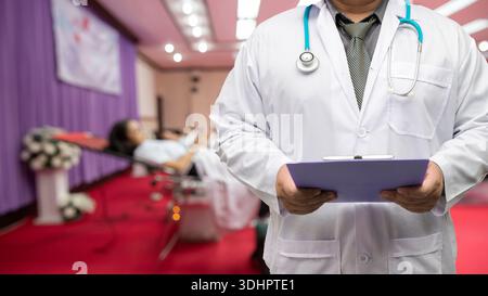 Doctor in gown uniform with stethoscope standing and holding chart diagnose in blood donor room. Stock Photo