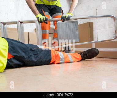Male body lying on the floor after a work accident.Fallen ladder.Request help from co-workers Stock Photo