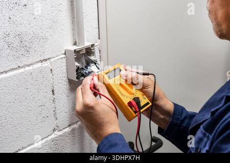 Close-up on an hands of electrician fixing an electrical outlet and measuring the voltage at a factory - improvement concepts Stock Photo