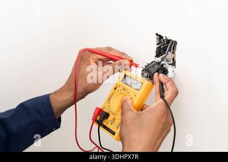 Close-up on an hands of electrician fixing an electrical outlet and measuring the voltage at a house. Stock Photo
