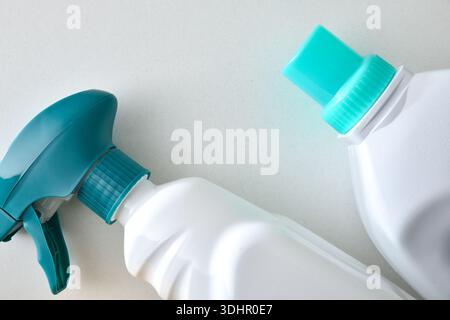 Macro detail of the top of white plastic bottles with green caps with cleaning and disinfection products on a white table. Top view. Stock Photo