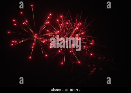 View of vibrant red fireworks burst against the inky night sky, illuminating the darkness with a dazzling display of light, Mandurah, Western Australi Stock Photo