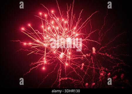 View of vibrant red fireworks burst against the inky black sky, illuminating the night with fleeting sparks and smoky trails, Mandurah, Western Austra Stock Photo