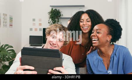 Trio of Friends Collaborating in Modern Office on Tablet for Startup Project Stock Photo