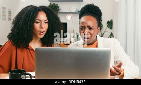 Diverse Startup Team Shocked and Focused While Reviewing Results On Laptop In Modern Office Stock Photo