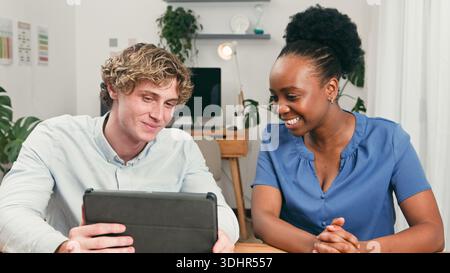Two Friends Collaborate At A Modern Startup Desk Using Tablet In A Bright Office Stock Photo
