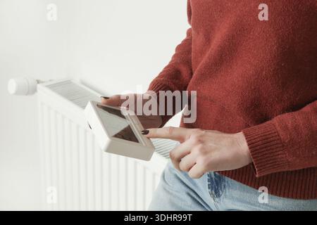 Woman Adjusting Programmable Thermostat for Home Heating and Cooling Control, Close Up Stock Photo