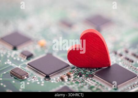 Small red heart on computer circuit board. Internet dating concept. Stock Photo