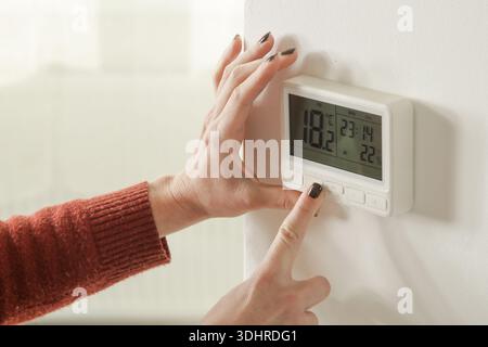 Woman Adjusting Programmable Thermostat for Home Heating and Cooling Control, Close Up Stock Photo
