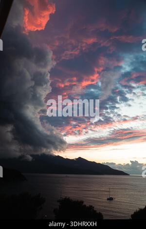 Dramatic sunset with vibrant clouds over the ocean, showcasing a contrast between light and shadow. Elba Italy Stock Photo