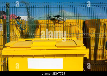 Fishing nets piled behind trash containers The concept of pollution Stock Photo