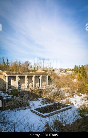 Ruins of the abandoned Soviet Medea Sanatorium in Tskaltubo, Georgia, partially covered with snow. A decaying symbol of post-Soviet architecture and f Stock Photo