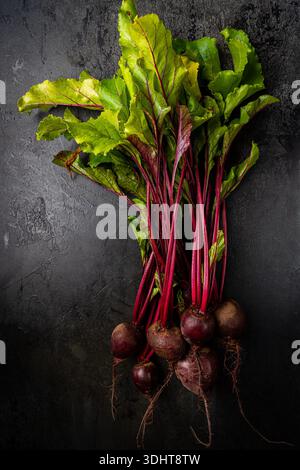 Fresh red beetroot with herbage green leaves over black background, top view Stock Photo