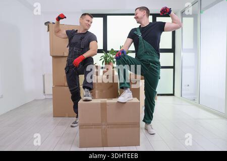 Movers celebrate teamwork in a bright, modern room filled with boxes and warm energy during a busy day Stock Photo