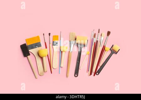 Colored artistic paintbrushes, roller brushes and sponge foam brushes on a pink background with copy space Stock Photo