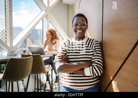 Black woman smiling confidently in modern office space Stock Photo