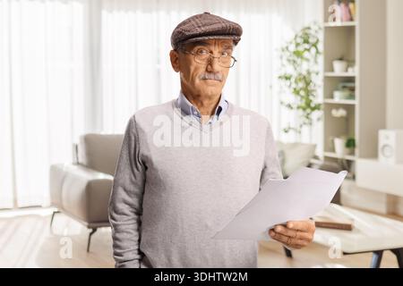 Senior man holding documents and thinking at home Stock Photo