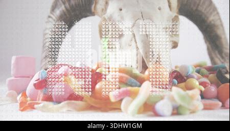 Displaying bleached horned skull sitting on white tabletop, showing gummy worms and jellybeans Stock Photo