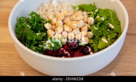 Chickpeas salad bowl with mixed greens and fresh toppings, healthy food photography top view in a white bowl. Stock Photo