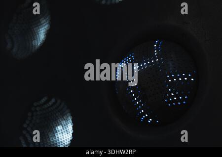 An abstract background with perforated spheres emitting tiny points of light against a black background. The dotted surface creates a futuristic, mood Stock Photo