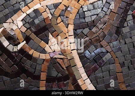 A close-up abstract photo of a mosaic made from small square tiles in dark browns, beiges, and grays, forming flowing curves and intersecting lines. R Stock Photo