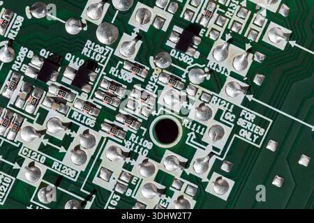 Close-up photo of a green printed circuit board featuring solder joints and traces. This image conveys electronics engineering, manufacturing, and tec Stock Photo