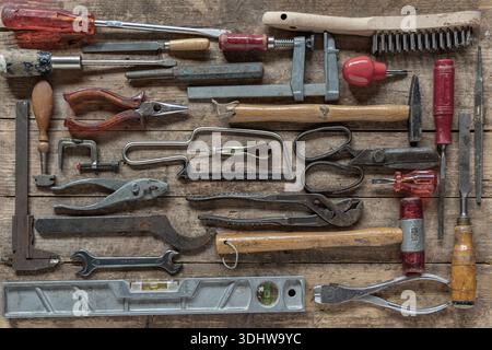 Vintage working tools displayed on wooden board wint grunge and dirty stains. Stock Photo