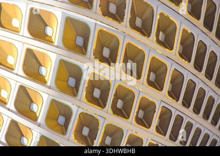 Abstract architectural detail of a white grid structure featuring repetitive, recessed golden panels with a modern, geometric design. Stock Photo