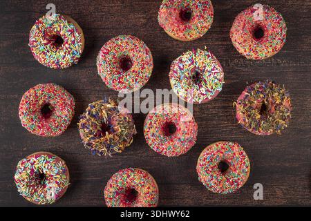Different donuts arranged with colorful sprinkles on rustic wooden table Stock Photo