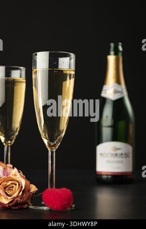 Two glasses on a black background with roses and a red heart Stock Photo