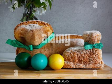 Easter still life with traditional lamb cakes, painted eggs and blooming cherry branches in vase, spring holiday baking concept Stock Photo