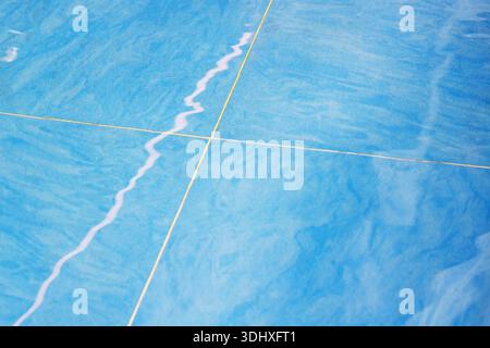 abstract blue fabric with stitched seams, closeup of intersecting dashed yellow stitch and pale wavy mark, macro Stock Photo