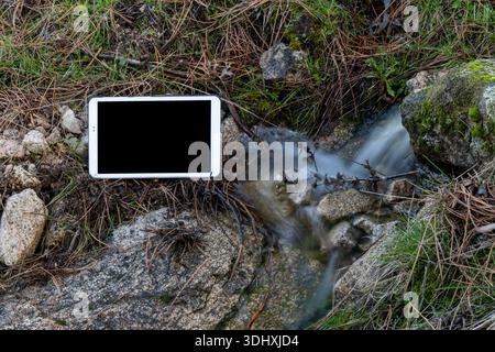 Modern tablet placed beside river outdoors Stock Photo