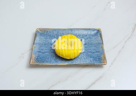 A warm still life featuring a chocolate donut with colorful sprinkles, a lemon-glazed donut, and a simple cinnamon and sugar donut, all on retro check Stock Photo
