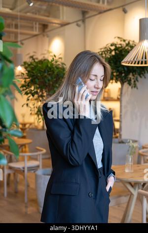 Happy businesswoman cafe executive enjoying business conversation with partners on smartphone. Stock Photo