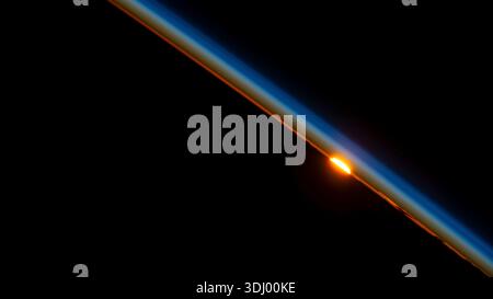 The sun just below the horizon and illuminating Earth's atmosphere, as photohgraphed from orbit. The ISS orbits Earth every 90 minutes, meaning the crew experiences 16 sunrises and sunsets daily.  A photograph taken from the International Space Station on 9 July 2023. An optimised version of an original NASA image: Credit: NASA Stock Photo