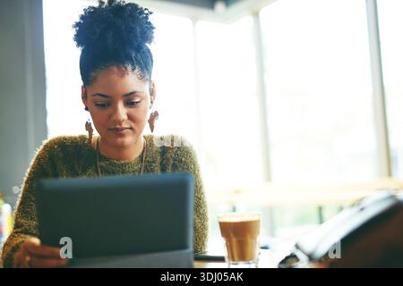 University student, girl and tablet with reading in cafe for online learning, study break and research. Education, african person and digital tech in Stock Photo