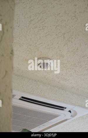 Smoke detector installed on ceiling in indoor area Stock Photo